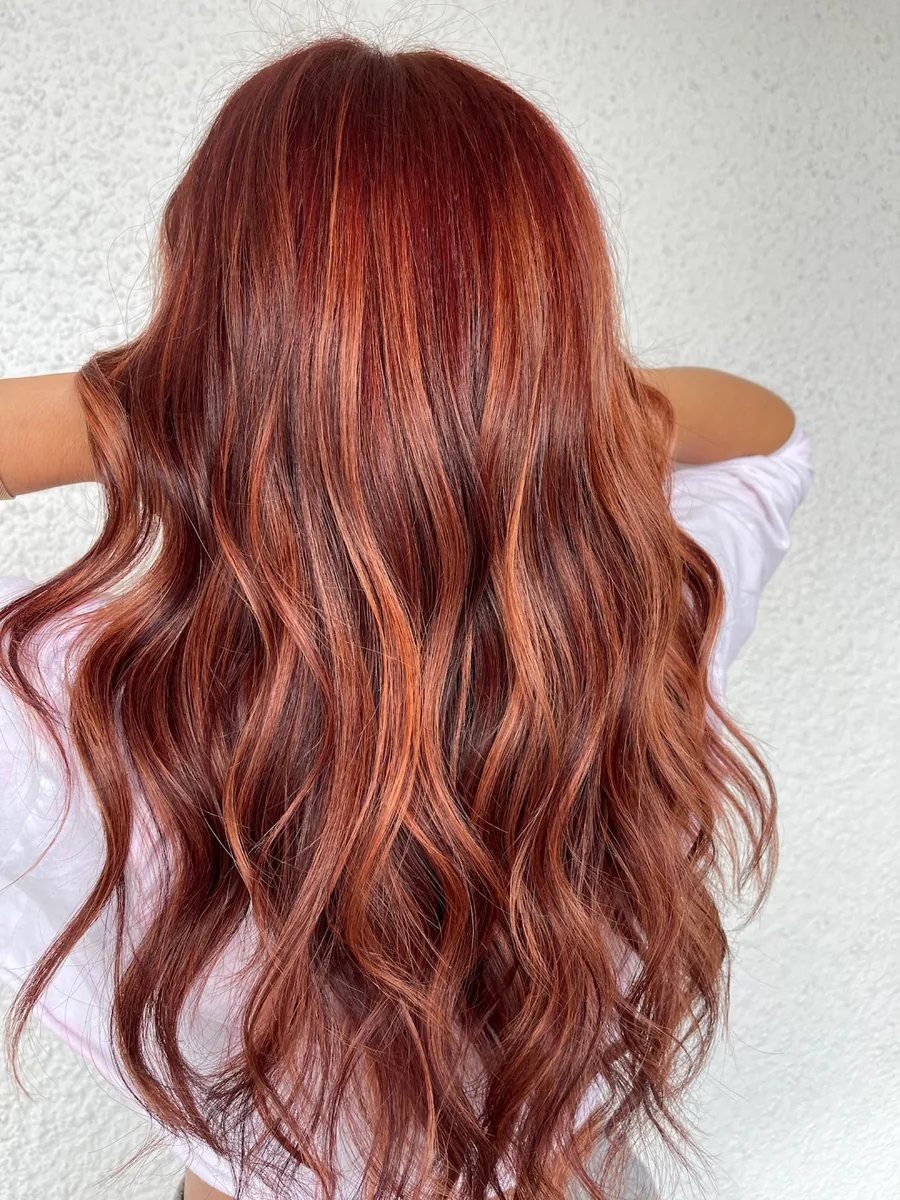 Long wavy hair coloured in warm copper and auburn tones, seen from behind